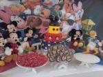 Mesa decorada da turma da disney com doces personalizados.