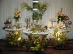 Mesa de café, outra de petit-four e outra de doces. Decoração c/ arranjos tropicais de flores e plantas naturais.Doc.3-CF