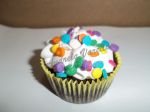 Mini cupcake recheado. Cobertura em marshmallow e confeitos coloridos.