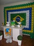 Painel de balões nas cores da copa (verde, amarelo, azul e branco); bolo provençal; mesa provençal; kachepot com buchinos e arranjo com fuleco