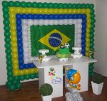 Painel de balões nas cores da copa (verde, amarelo, azul e branco); bolo provençal; mesa provençal; kachepot com buchinos e arranjo com fuleco
