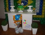 Painel de balões nas cores da copa (verde, amarelo, azul e branco); bolo provençal; mesa provençal; kachepot com buchinos e arranjo com fuleco