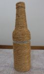 Garrafa decorada com sisal e faixa de strass.